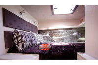 Nova Luxe Elight 44 Electric Boat Small bedroom with a bed and decorative pillows, featuring a large wall-mounted screen displaying an abstract design.