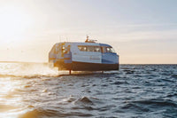 Candela P-12 Ferry boat on water with a sunset or sunrise in the background