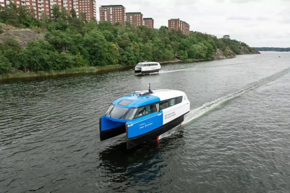 Candela P-12 Blue and white ferry boat on a river with greenery and buildings in the background