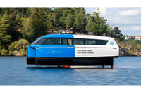 Candela P-12 Blue and white electric ferry on a lake with trees and buildings in the background