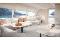 Candela P-12 Shuttle Electric Ferry Modern yacht interior with white sofas, a coffee table, and scenic views of water and mountains.