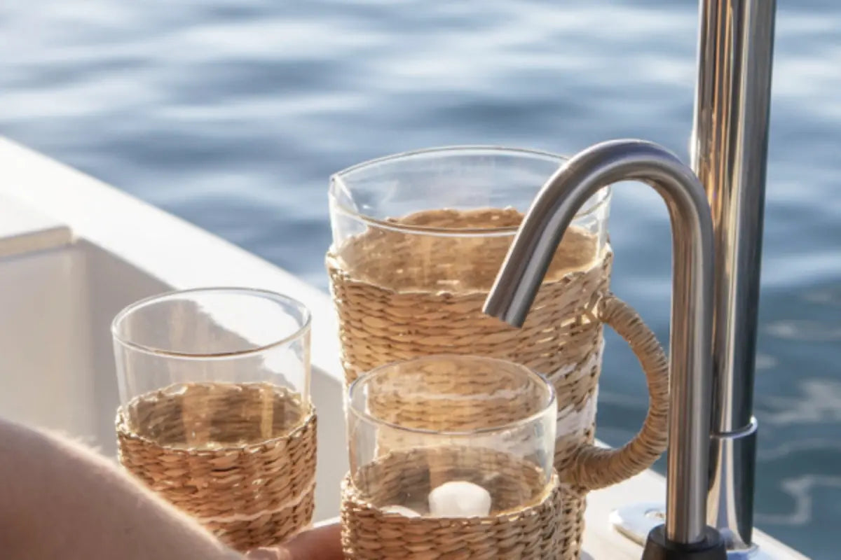 Duffy Balboa 20 Glass mugs with wicker sleeves and a metal faucet on a boat with water in the background