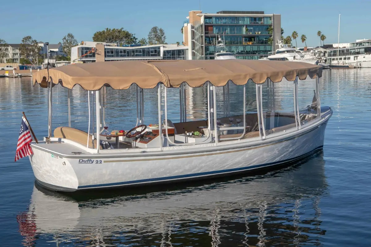 White Duffy Bay Island 22 Electric Boat with a canopy on a body of water with buildings in the background