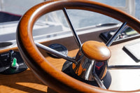 Close-up of a Duffy Bay Island 22 Electric Boat steering wheel with wooden rim and metal spokes.