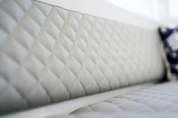 Duffy Cat 16 Electric Boat Close-up of a quilted white sofa with a blurred background