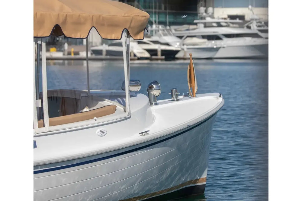 Duffy Cuddy Cabin 22 Electric Boat with a canopy on a body of water with other boats in the background
