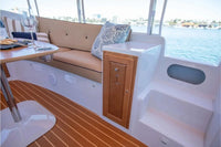Interior of a Duffy Cuddy Cabin 22 Electric Boat with beige sofa, wooden floor, and table.