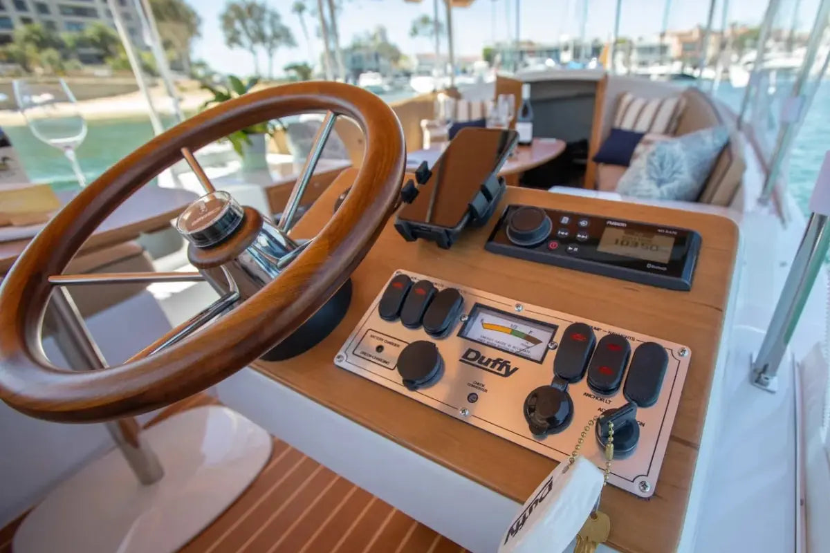 Duffy Cuddy Cabin 22 Electric Boat steering wheel and dashboard with control panel on a yacht deck.