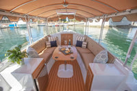 Interior of a Duffy Cuddy Cabin 22 Electric Boat with seating area, table, and decor on a body of water.