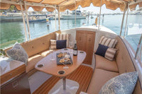 Interior of a Duffy Cuddy Cabin 22 Electric Boat with seating area and table, waterfront view outside