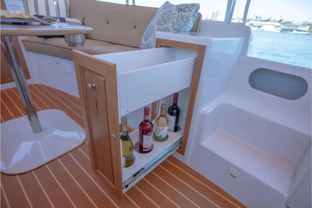 Open cabinet on a Duffy Cuddy Cabin 22 Electric Boat with drinks inside, showing a waterfront view.