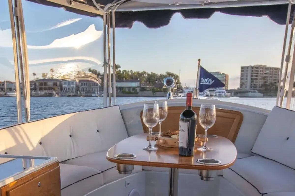 Duffy Snug Harbor 18 Electric Boat interior with wine bottle and glasses on a table, waterfront view.