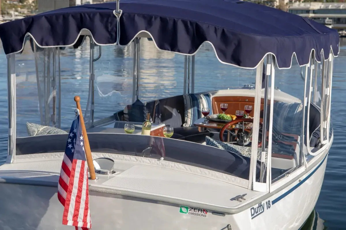 Duffy Snug Harbor 18 Electric Boat with a canopy and American flag on a body of water