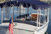Duffy Snug Harbor 18 Electric Boat with a canopy and American flag on a body of water