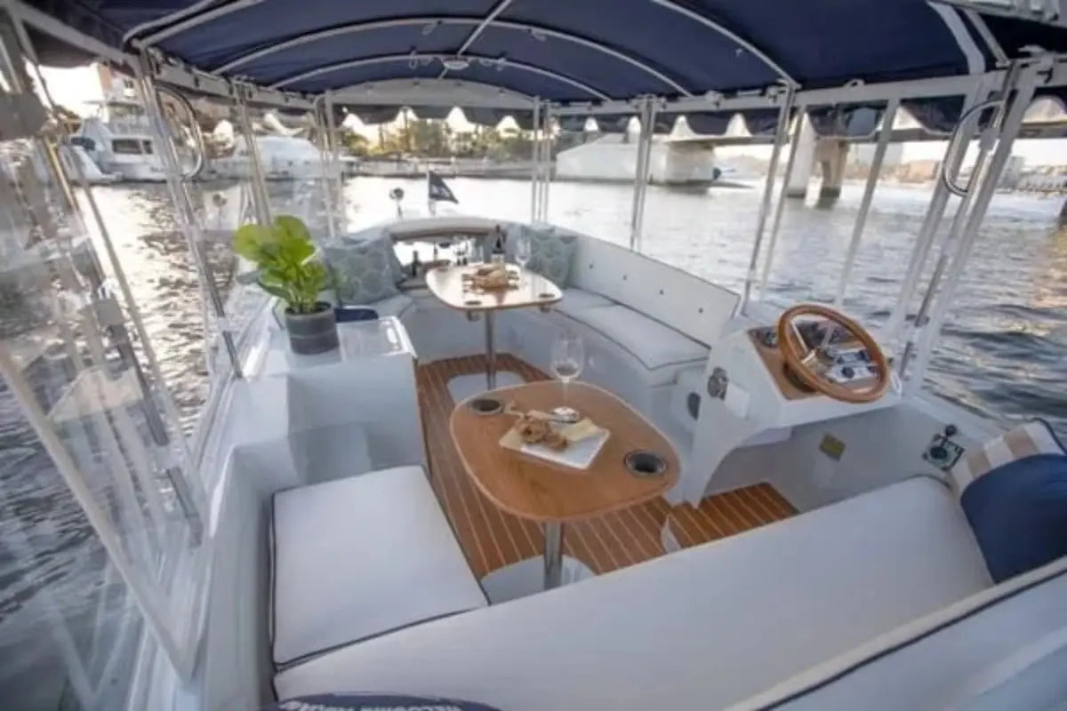 Interior of Duffy Snug Harbor 18 Electric Boat with seating area, table, and steering wheel.
