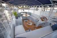 Interior of Duffy Snug Harbor 18 Electric Boat with seating area, table, and steering wheel.