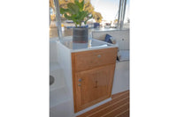 Wooden cabinet with a drawer and anchor emblem on Duffy Snug Harbor 18 Electric Boat deck.