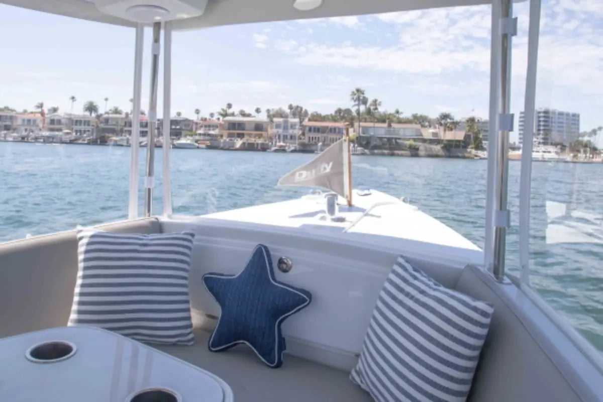 Interior of Duffy Sun Cruiser 23 Electric Boat with cushions and a starfish decoration, overlooking a waterfront view.