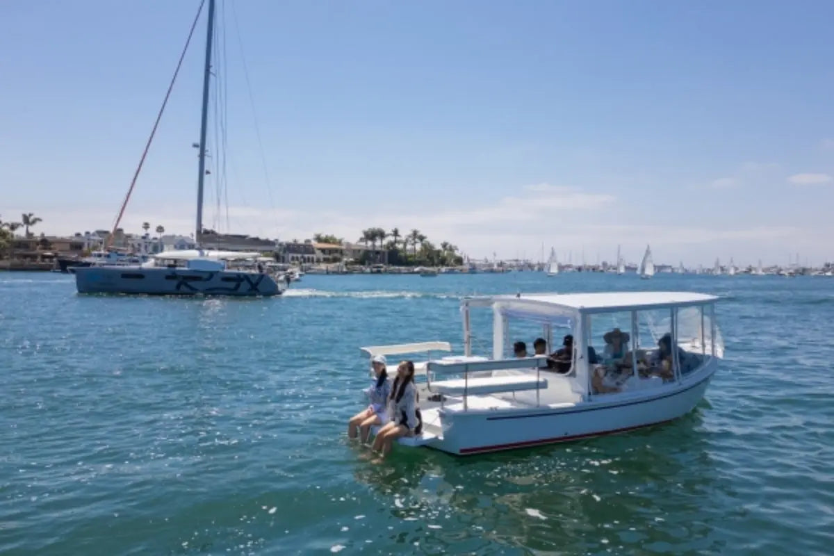 Duffy Sun Cruiser 23 Electric Boat with passengers on a body of water under a clear blue sky.