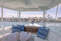 Interior of Duffy Sun Cruiser 23 Electric Boat with blue and white striped cushions, table, and view of water and buildings.