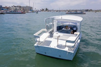 Duffy Sun Cruiser 23 Electric Boat with a canopy on a body of water with buildings in the background