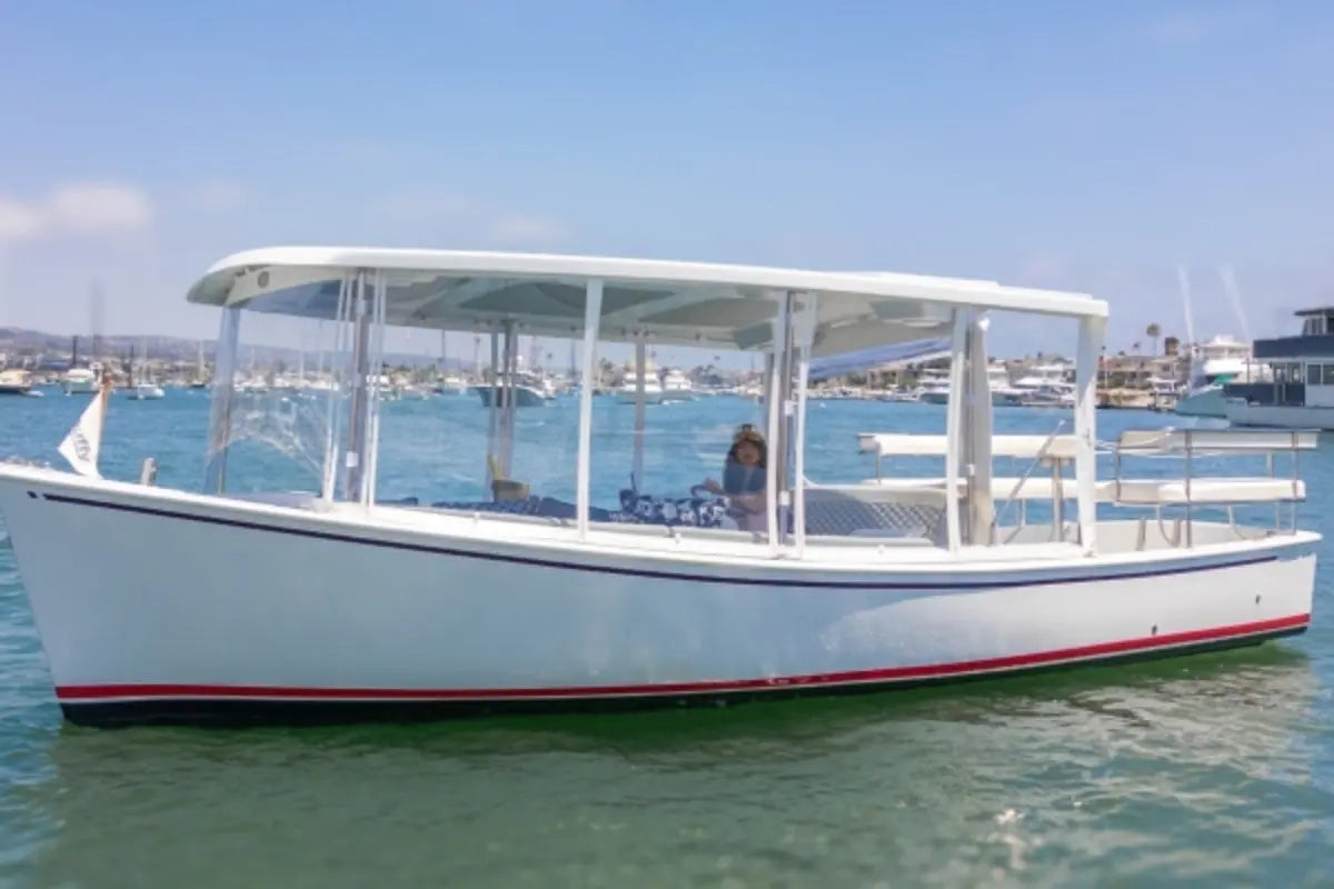 Duffy Sun Cruiser 23 Electric Boat with a canopy on a body of water under a clear blue sky.