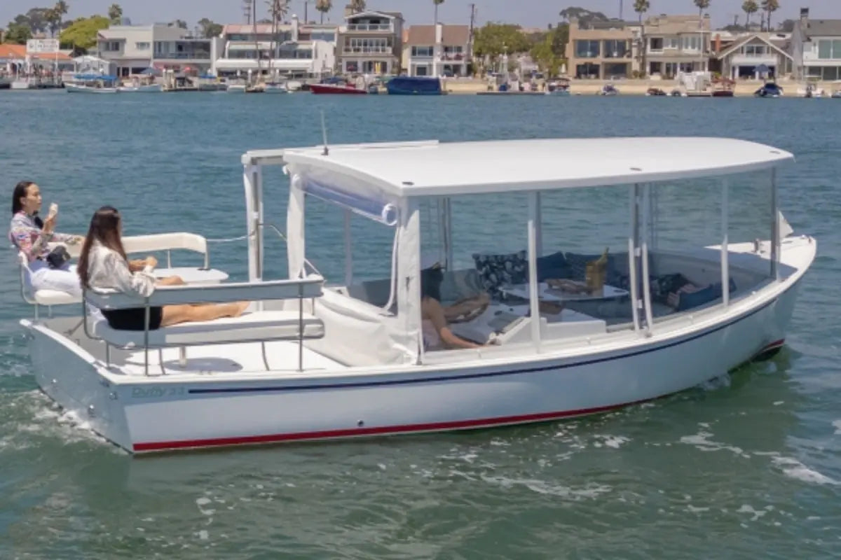 Duffy Sun Cruiser 23 Electric Boat with people on a body of water, surrounded by buildings.
