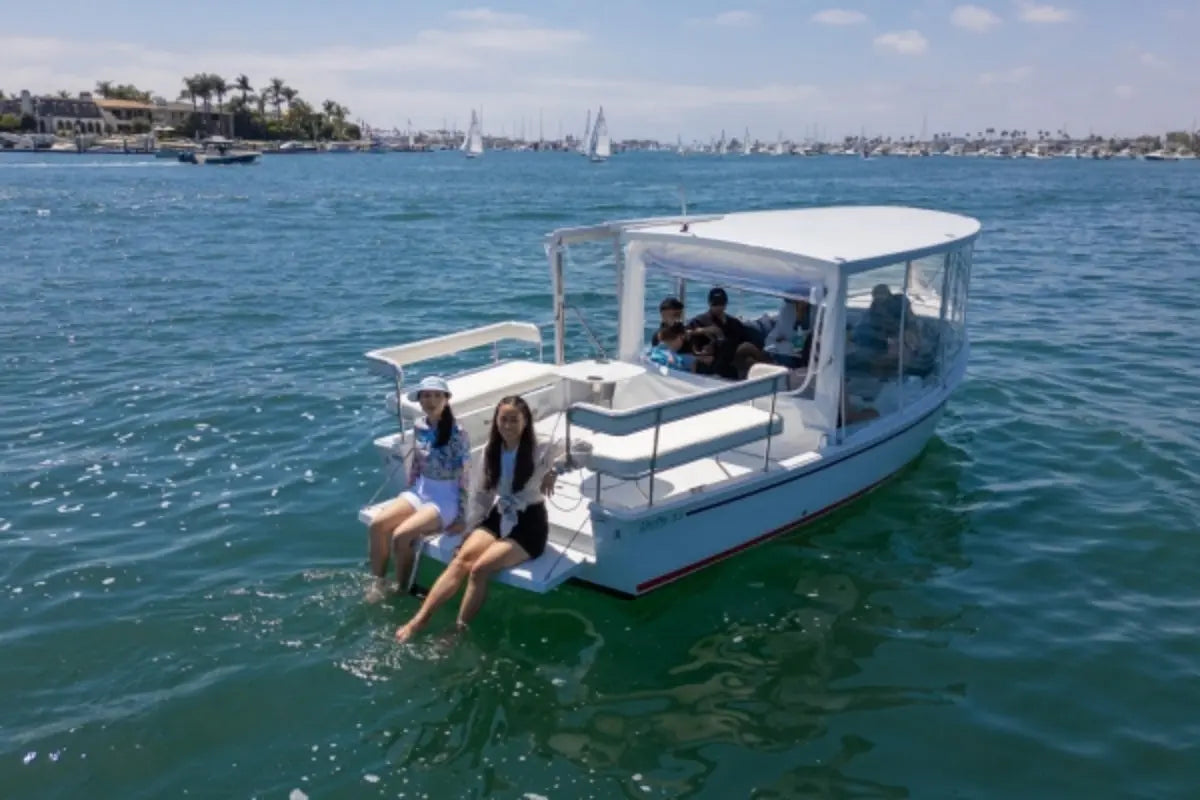 People on Duffy Sun Cruiser 23 Electric Boat in the water with a cityscape in the background