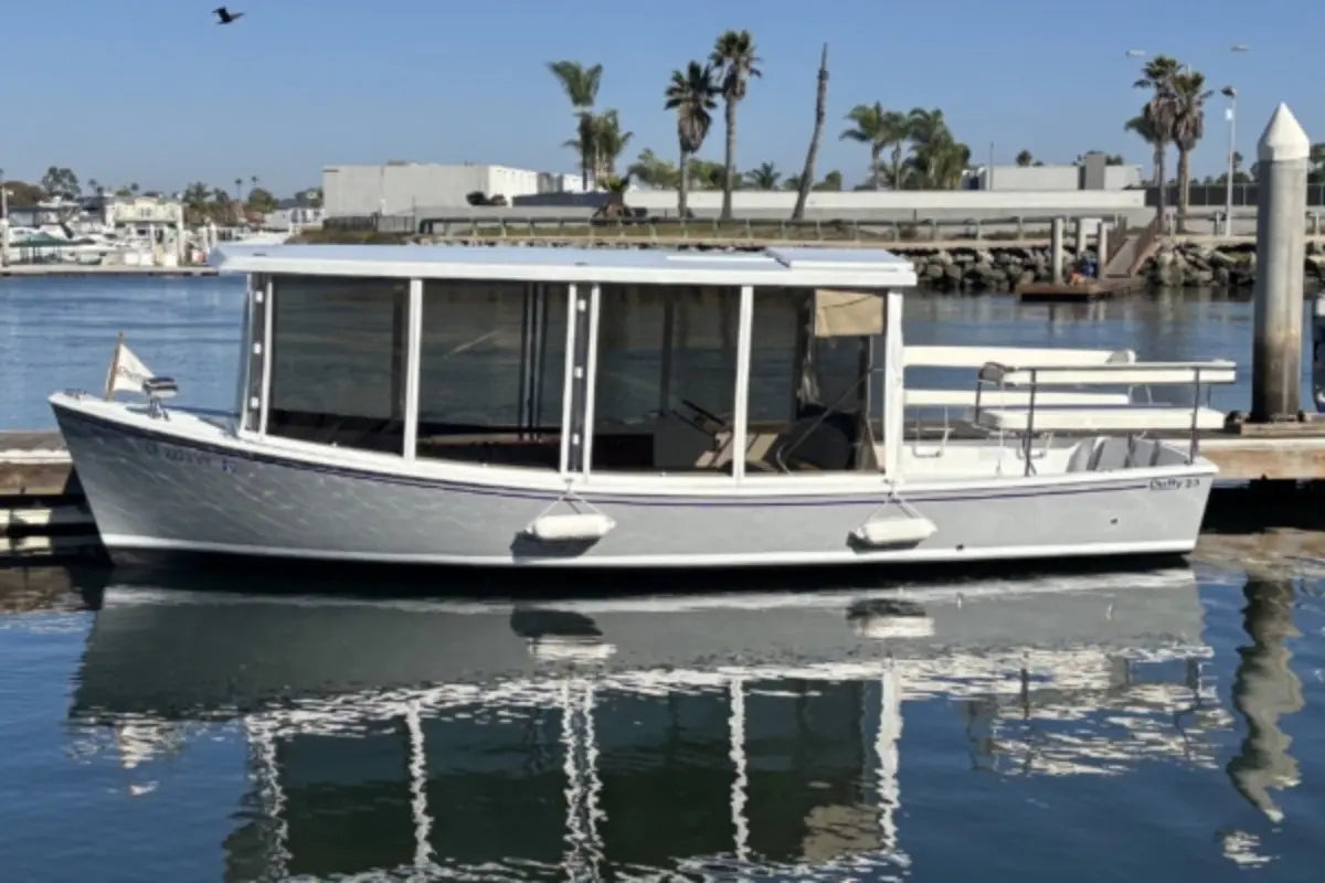 Duffy Sun Cruiser 23 Electric Boat docked at a marina with palm trees and buildings in the background