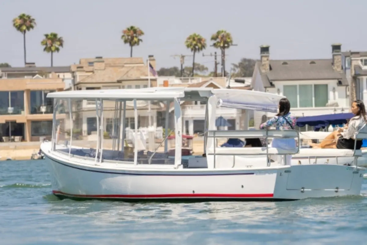 Duffy Sun Cruiser 23 Electric Boat on water with palm trees and houses in the background