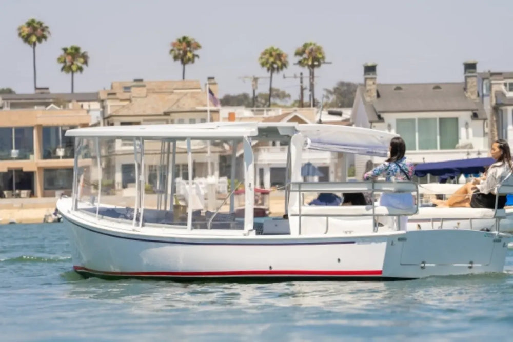 Duffy Sun Cruiser 23 Electric Boat on water with palm trees and houses in the background
