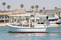 Duffy Sun Cruiser 23 Electric Boat on water with palm trees and houses in the background
