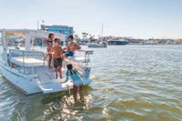 People on a Duffy Sun Cruiser 23 Electric Boat in the water with a clear sky and buildings in the background.