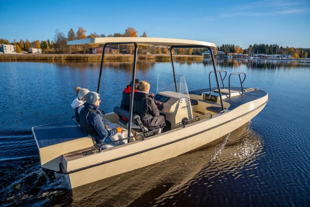 Elvene Amber Solar Electric Boat on a lake with people inside, surrounded by trees and clear sky