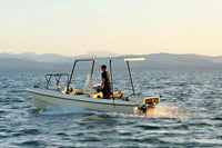 Person on Elvene Amber Solar Electric Boat in the water with mountains in the background