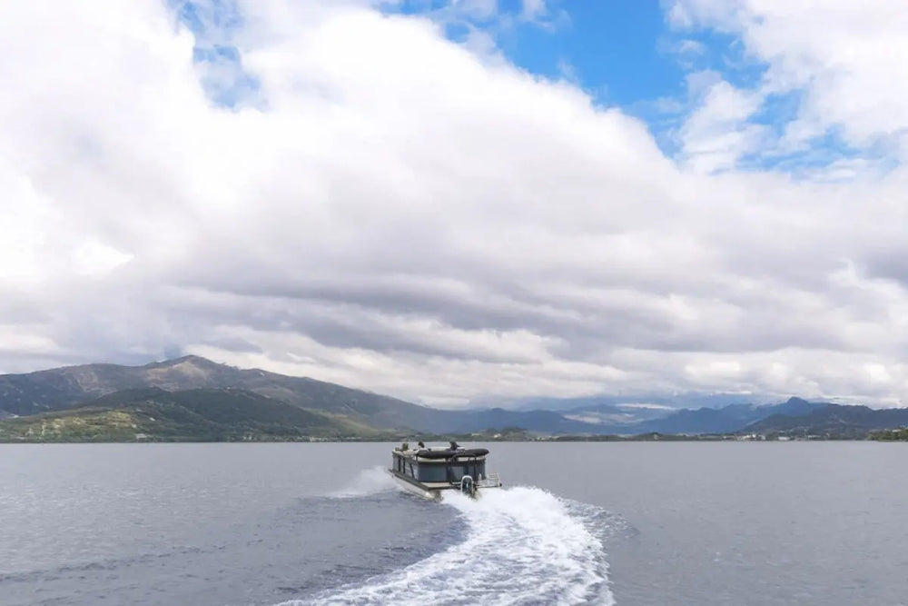 Flux Flagship Discover Electric Boat on a lake with mountains in the background under a partly cloudy sky
