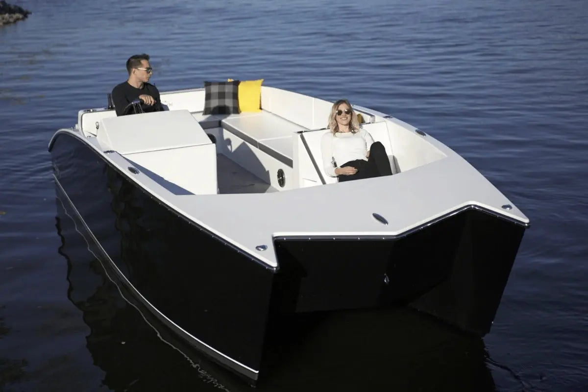 Two people in a small Flux GFX Stealth Electric Catamaran Boat on calm water