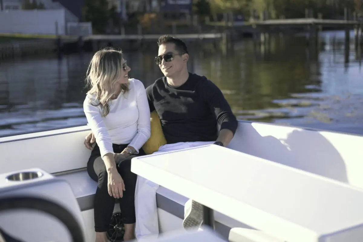 Two people sitting on Flux GFX Stealth Electric Catamaran Boat by a body of water