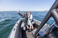 Two people on Flux Highfield Sport 660 Electric Boat taking a selfie with a clear blue sky and water background