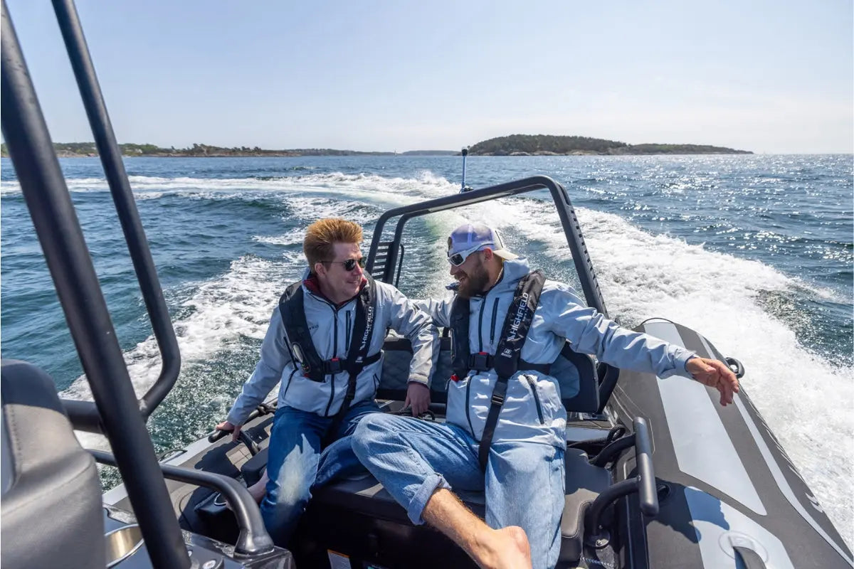 Two people on Flux Highfield Sport 660 Electric Boat in the water with an island in the background