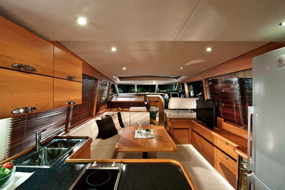 Greenline 40 Electric Yacht Modern kitchen interior with wooden cabinets, stainless steel appliances, and a dining table.