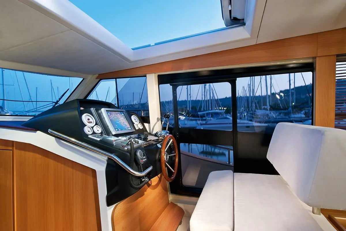Greenline 40 Electric Yacht interior with dashboard, steering wheel, and view of marina through large windows.