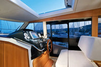 Greenline 40 Electric Yacht interior with dashboard, steering wheel, and view of marina through large windows.