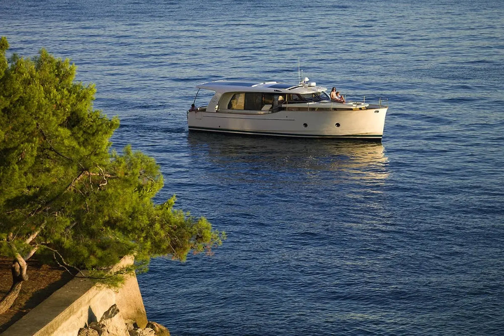 Greenline 40 Electric Yacht on a calm blue sea with green trees in the foreground