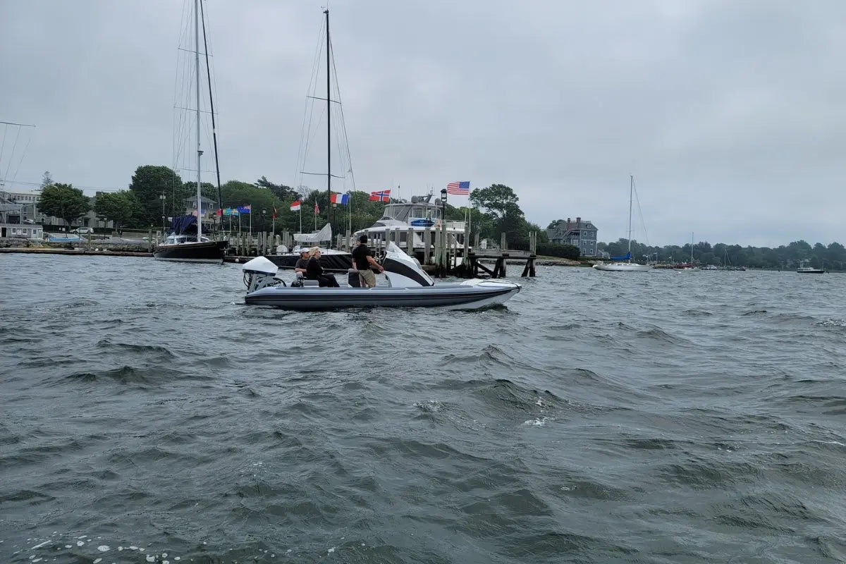 Hyfoil 22 Electric Boat on water with a dock and flags in the background