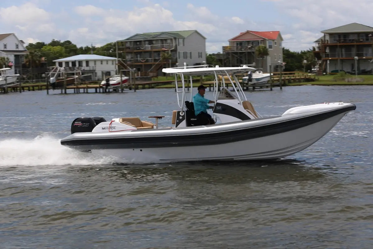 Hyfoil 28 Electric Boat with a black stripe on a body of water with houses in the background