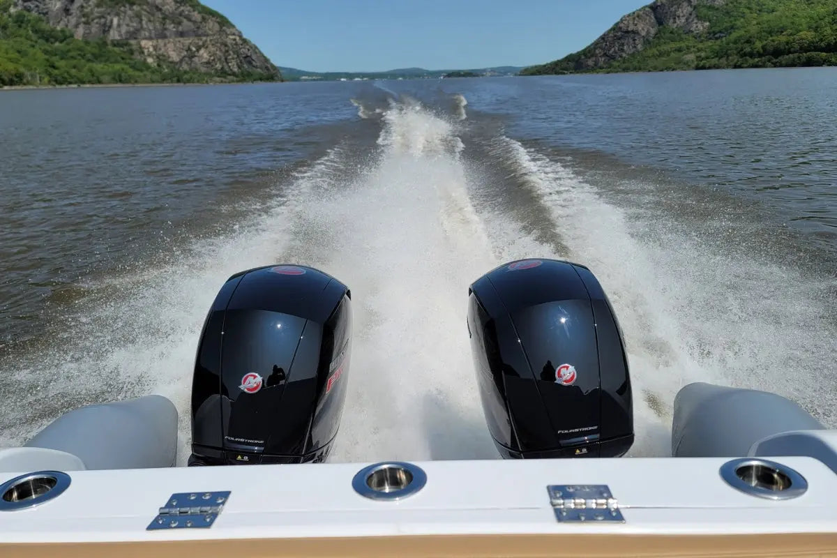 Two outboard motors on Hyfoil 28 Electric Boat speeding across a lake with mountains in the background.