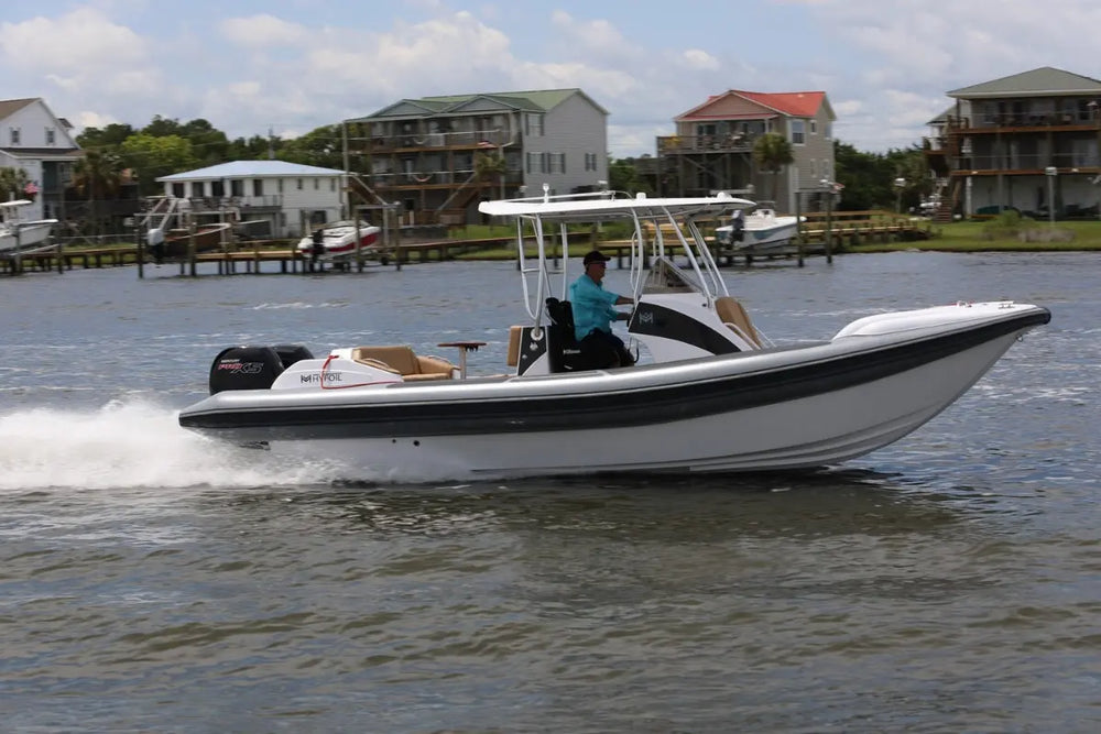 Hyfoil 28 Electric Boat with a black stripe on a body of water with houses in the background