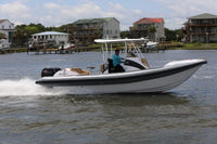 Hyfoil 28 Electric Boat with a black stripe on a body of water with houses in the background
