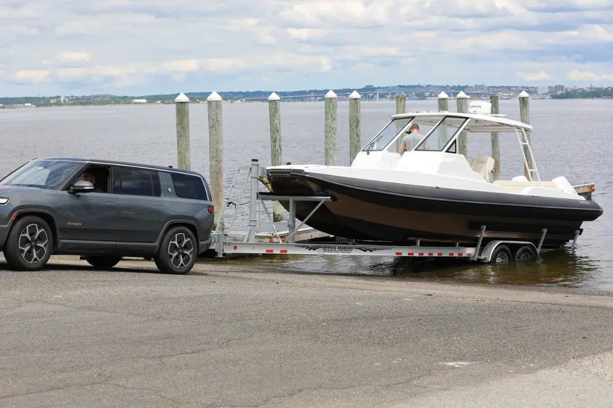SUV towing Hyfoil 32 Electric Boat on a trailer by a dock with water and sky in the background